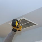 Technieker monteert een ventilatierooster in het plafond